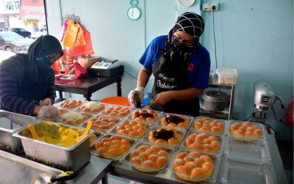 Pemilik perniagaan Roti Gebhoo Nazidah Ali, 38, (kanan) bersama salah seorang pekerjanya sibuk menyiapkan roti perisa coklat dan keju semasa ditemui Bernama di kedainya. - Foto Bernama