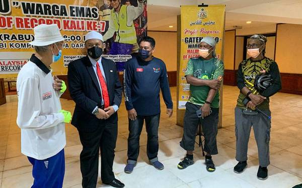 Pak Wan (kiri) mendengar nasihat daripada Wan Roslan sebelum memulakan perjalanan.