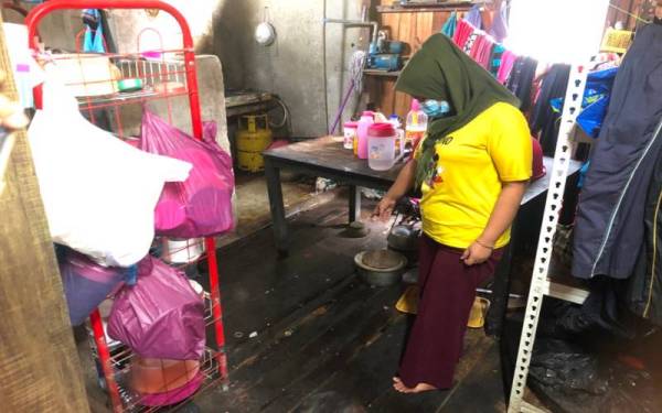Siti Aishah menunjukkan keadaan lantai rumah mereka yang reput.