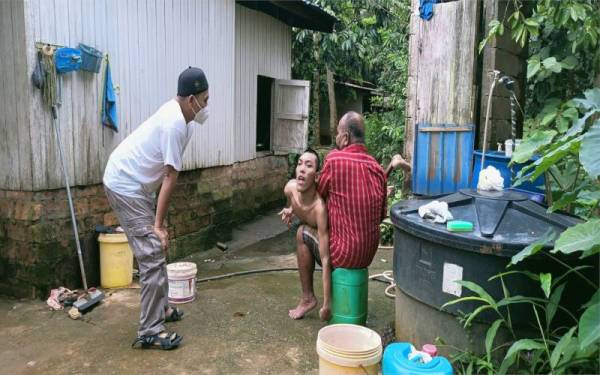 Abdullah memandikan Muhammad Khairul Anuar sambil diperhatikan oleh Raja Shamri sementara Muhammad Hakimi mengikuti pengajian dalam talian.