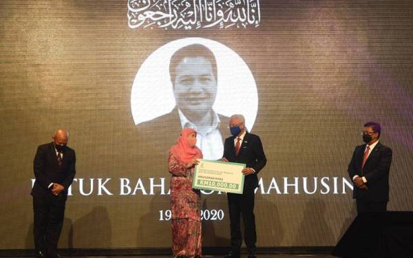 Perdana Menteri Datuk Seri Ismail Sabri Yaakob (dua, kanan) menyampaikan Anugerah Khas kepada isteri Allahyarham Datuk Baharom Mahusin daripada Sinar Harian yang memenangi Posthumos sebanyak RM10,000 berserta sijil dan trofi pada Majlis Malam Wartawan Malaysia 2021 di sebuah hotel pada Selasa. - Foto Bernama