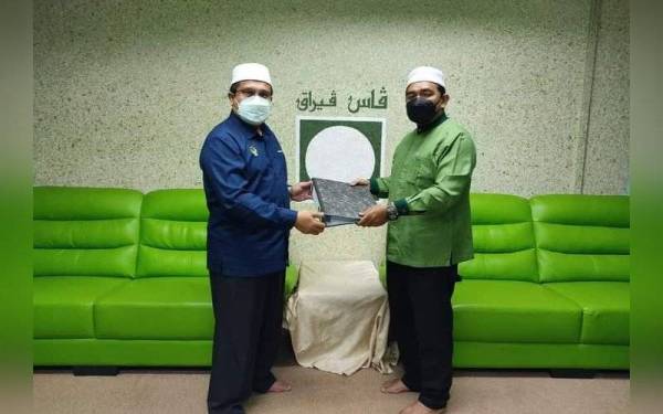 Mohd Akmal (kiri) membuat simbolik penyerahan jawatan Setiausaha Pas Perak kepada Fairuz Hafiiz di Pejabat Pas Perak, di Ipoh pada Khamis.