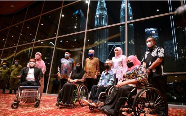 Perdana Menteri Datuk Seri Ismail Sabri Yaakob (belakang, tiga, kanan) bersama golongan OKU ketika merasmikan Sambutan Hari OKU Sedunia Peringkat Kebangsaan Tahun 2021 di Pusat Konvensyen Kuala Lumpur pada Jumaat. Turut hadir, Menteri Pembangunan Wanita, Keluarga dan Masyarakat Datuk Seri Rina Mohd Harun (belakang, dua, kanan). - Foto Bernama