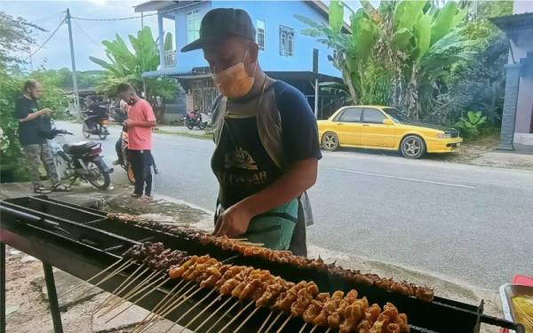 Mohd Suriadi membantu isterinya membakar sate.