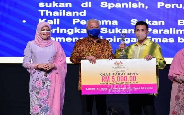 Ismail Sabri (tengah) dan Rina (kiri) menyerahkan Anugerah Khas Paralimpik kepada atlet paralimpik badminton Cheah Liek Hou (kanan) pada Majlis Sambutan Hari OKU Sedunia Peringkat Kebangsaan Tahun 2021 di Pusat Konvensyen Kuala Lumpur hari ini. Foto Bernama
