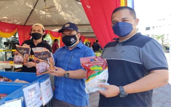Muhamad Zikril Azan (tengah) bersama penjual ayam (kiri) ketika Program Jualan Keluarga Malaysia di Dataran 5C, Taman Putra Perdana, Sepang pada Sabtu.