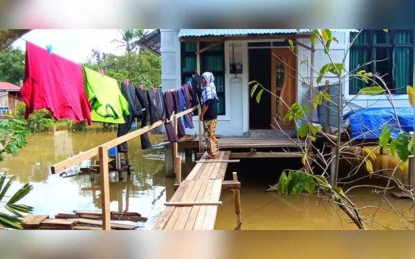 Zarina menggunakan kemudahan titi kayu yang dibina oleh suaminya untuk menjemur kain di ampaian.