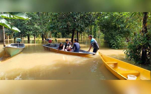 Mohd Khairul (duduk, kanan) bersama keluarganya menjadikan perahu sebagai pengangkutan utama sejak Khamis lalu selepas kawasan rumah ditenggelami air banjir.