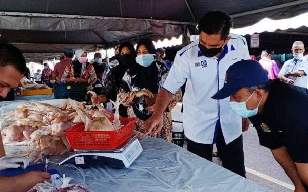 Adnan (kanan) melihat timbangan ayam yang dijual serendah RM7.90 sekilogram pada Program Jualan #Keluarga Malaysia Peringkat Parlimen Rantau Panjang di Lubok Jong pada Sabtu.