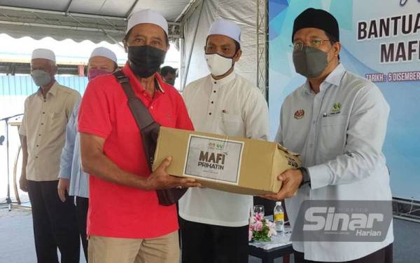 Ahmad Tarmizi (kanan) menyerahkan bakul bantuan makanan kepada seorang pesawah pada Majlis Penyerahan Bantuan Bakul Makanan MAFI Prihatin MADA di Yan pada Ahad.