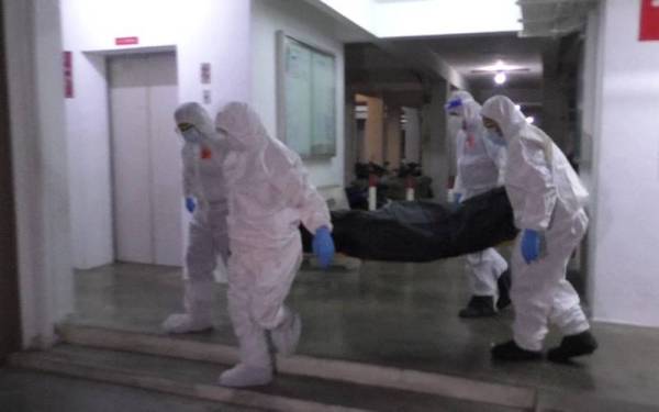 Anggota polis lengkap berpakaian perlindungan diri mengangkat mayat mangsa yang ditemui mati dalam sebuah rumah di Apartmen Sri Nipah, Sungai Nibong, Georgetown malam Ahad.