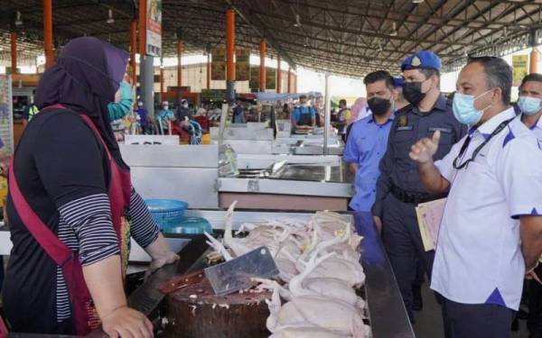 Adnan (kanan) bertanya sesuatu kepada peniaga ayam ketika Program Walkabout Skim Harga Maksimum Keluarga Malaysia di Pusat Transformasi Luar Bandar (RTC), Tunjong, Kota Bharu pada Selasa.