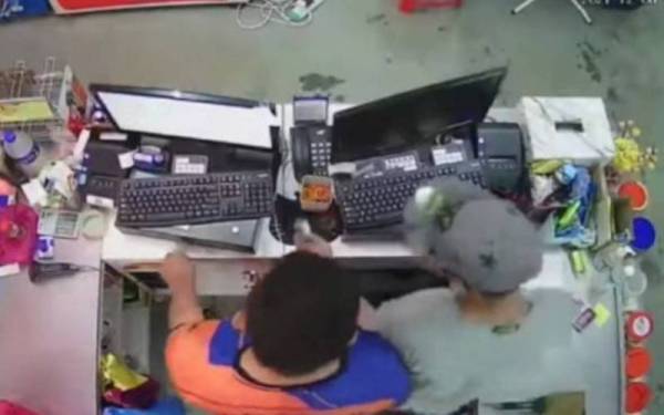 Suspek yang memakai topi, pelitup muka dan cermin mata hitam menyerbu dalam ruangan kaunter untuk mengambil wang tunai. - Foto PDRM