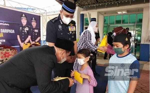 Md Tahir (kiri) mewakili Raja Perempuan Tengku Anis menyampaikan kurniaan wang tunai kepada penerima pada majlis yang berlangsung di IPD Pasir Mas pada Selasa.