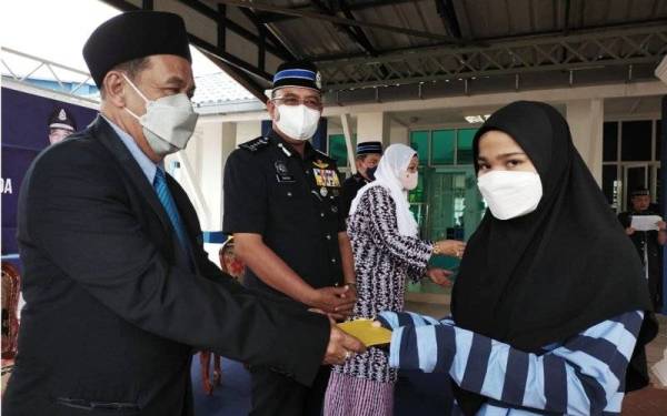 Shafien (dua dari kiri) dan Md Tahir (kiri) mewakili Raja Perempuan Tengku Anis menyampaikan sumbangan kotak rezeki daripada kurniaan Istana kepada balu dan anak-anak yatim Polis Diraja Malaysia (PDRM) Kontinjen Kelantan di IPD Pasir Mas pada Selasa.