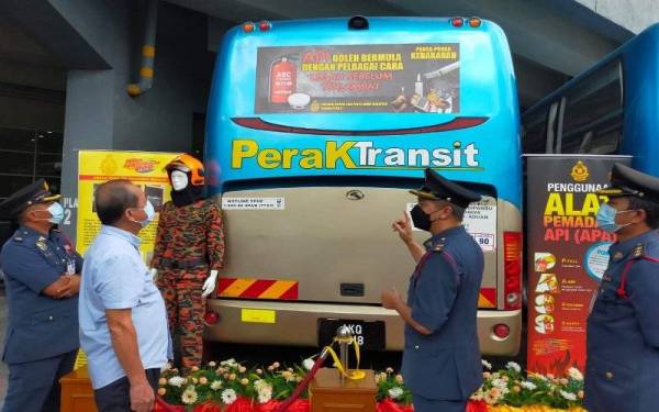 Syed Azman (dua dari kanan) melihat poster Kempen Keselamatan Kebakaran yang dipasang pada Bas Perak Transit di Terminal Bas Amanjaya, Meru Raya pada Khamis.