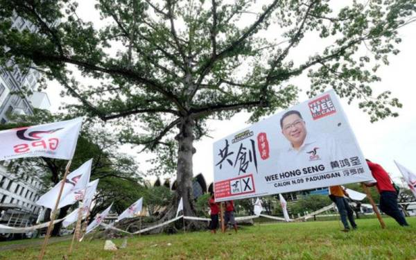 Poster calon GPS dinaikan di Padang Merdeka berlatar belakang pokok kekabu berusia 93 tahun yang masih teguh berdiri ketika tinjuaan sempena PRN Sarawak ke-12. - Foto Bernama
