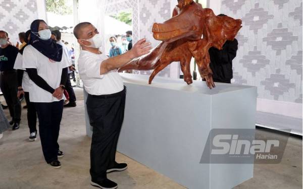 Saarani melihat arca yang dipamerkan di Festival Kesenian Antarabangsa Ipoh (IIAF) 2021 di PORT, Ipoh pada Sabtu.