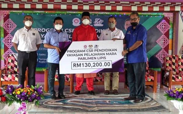 Mohd Nizar (dua,kiri) menyerahkan replika cek kepada Amin Nollah(kanan) yang disaksikan oleh Abdul Rahman (tengah) dalam majlis di SK Penjom, Lipis pada Sabtu.