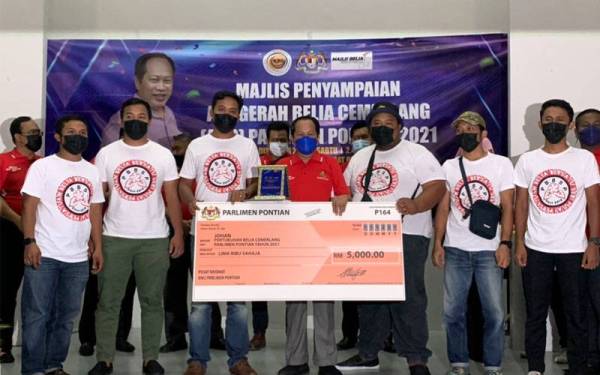 Ahmad Maslan (tengah) menyampaikan hadiah kepada pemenang Pertubuhan Belia Paling Cemerlang Parlimen Pontian di Dewan Muafakat Sungai Pinggan, Pontian pada Sabtu.