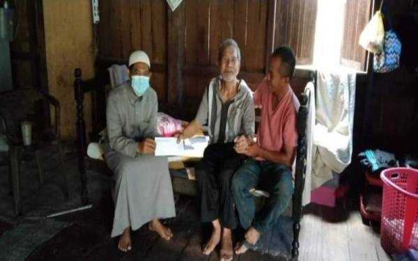 Amran (kanan) bersama bapanya, Awang menerima kunjungan Armin Azahari yang mewakili MAIK untuk menyampaikan sumbangan kepada keluarga berkenaan di Kampung Gertak Kangkong, Mengkebang, Kuala Krai pada Isnin.