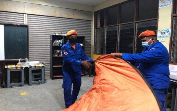 Anggota Angkatan Pertahanan Awam Malaysia (APM) Bandar Baharu memasang khemat untuk menempatkan mangsa banjir di pusat pemindahan sementara (PPS) Sekolah Kebangsaan Sungai Kechil Ulu, di sini. - Foto ihsan APM
