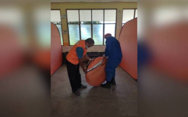 Anggota APM Bandar Baharu membuka khemah yang menempatkan mangsa banjir selepas PPD di SK Sungai Kechil Ulu ditutup pada Selasa. - Foto ihsan APM