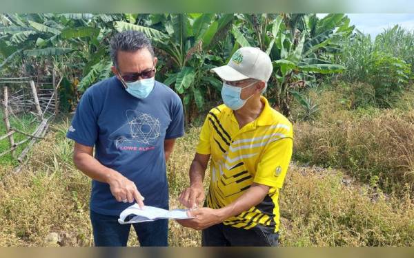 Amiruddin (kiri) bersama Meor Razak melihat pelan di kawasan terbabit bagi meninjau aduan penduduk.