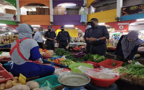 Aris (kanan) turun padang membuat pemantauan dan pelaksanaan
SHMKM di Pasar Siti Khadijah, Kota Bharu pada Rabu.