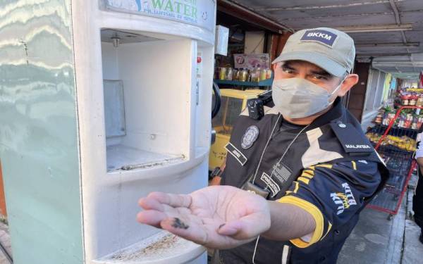 Mohd Wazir menunjukkan kotoran yang ditemui pada salah sebuah mesin jual air dalam Ops Sita pada Rabu.