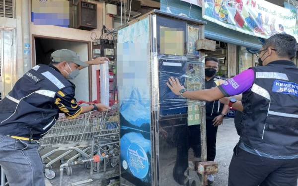 Mohd Wazir (kiri) bersama pegawai JKNPP menyita salah sebuah mesin jual air di Kepala Batas dalam Ops Sita pada Rabu.