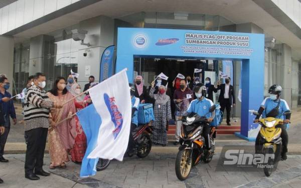 Ramlan memegang bendera Kemas ketika Flag Off Program Sumbangan Produk Susu Dutch Lady Milk Industries Berhad di lobi utama Kementerian Pembangunan Luar Bandar di Putrajaya pada Khamis.