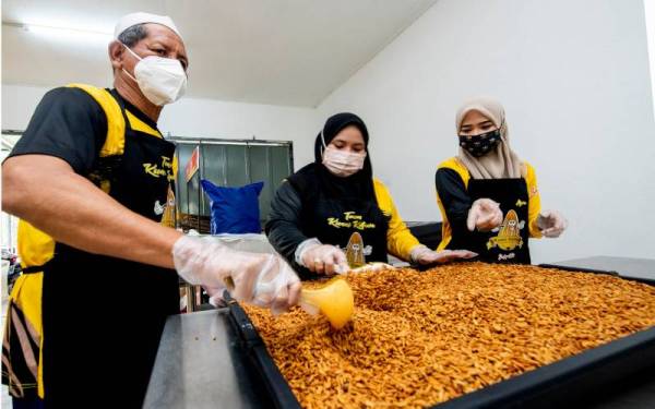Anis Ayuni (kanan) bersama pembantu ketika melakukan proses mengeringkan kuaci yang baru digoreng semasa ditemui Bernama di kilangnya, di Kampung Periok. - Foto Bernama