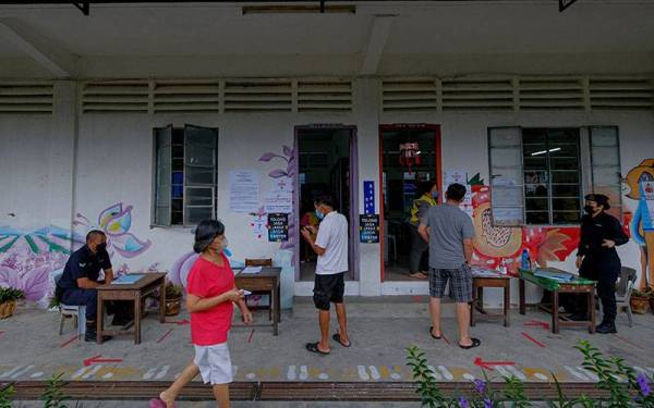 Beberapa orang pengundi yang tiba awal pagi ini untuk mengundi dilihat mematuhi prosedur operasi standard yang ditetapkan iaitu memakai pelitup muka dan melalui proses saringan suhu badan. -Foto Bernama