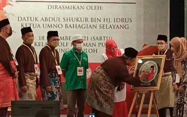 Abdul Shukur menurunkan tandatangan sebagai simbolik perasmian Mesyuarat UMNO Selayang di Kelab Rahman Putra, Sungai Buloh pada Sabtu.