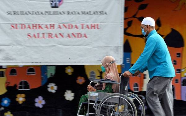 Warga emas, Safiah Hamzah, 81 dibantu anaknya menunaikan tanggungjawab mengundi bagi kawasan DUN N.73 Piasau di SK Jalan Bintang pada awal pagi Sabtu. - Foto Bernama