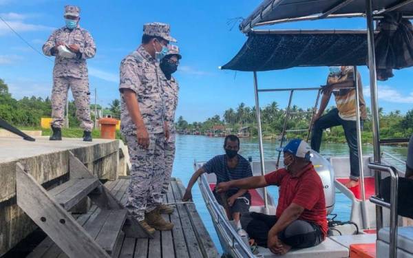 Syed Nur Adli (berdiri, kanan) mengingatkan nelayan tempatan semasa melakukan rondaan susulan Monsun Timur Laut yang sedang melanda perairan Kelantan ketika ini.