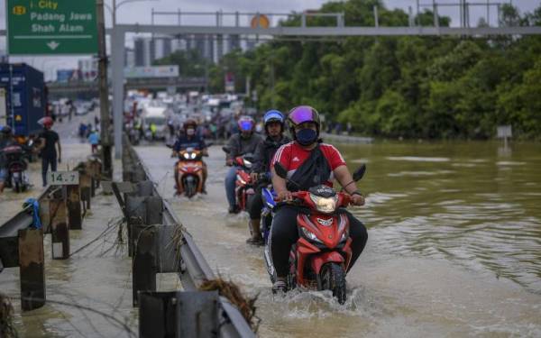  Beberapa penunggang motosikal meredah banjir kilat yang terjadi di Batu 3, Lebuhraya Persekutuan akibat limpahan air dari Sungai Damansara ketika tinjauan hari ini. - Foto Bernama