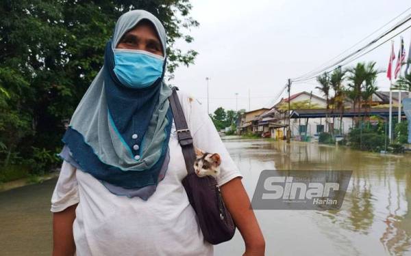 Wan Esah keluar terlebih dahulu dari rumah dengan membawa seekor kucing di dalam beg sebagai peneman di PPS nanti.