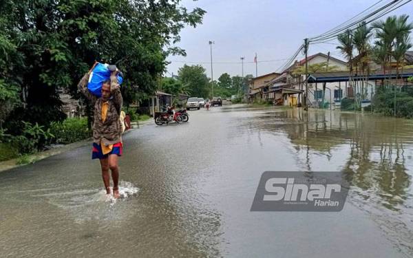 Saufi memikul barangan keperluan untuk berpindah awal bagi mengelakkan 'terperangkap' dengan banjir selepas air Sungai Golok makin melimpah masuk ke kawasan kampungnya.