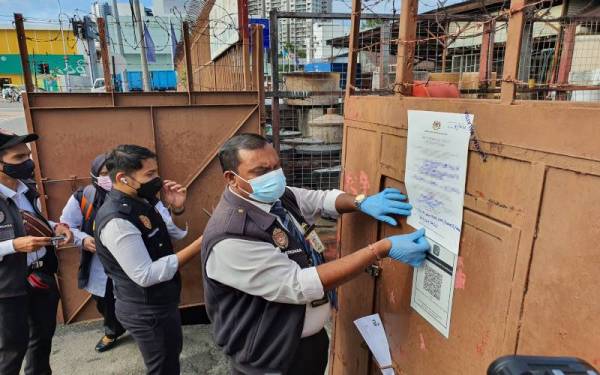 Pegawai BKKM menampal notis penutupan yang dikenakan terhadap kilang memproses kicap di Jalan Patani.