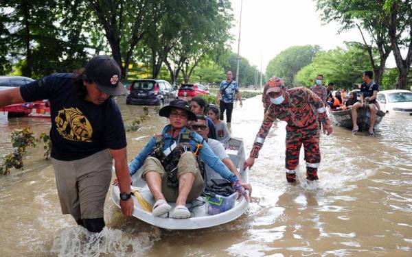 Anggota Jabatan Bomba dan Penyelamat Malaysia (JBPM) membantu membawa keluar mangsa banjir menggunakan bot ketika tinjauan di Taman Seri Muda Seksyen 25 pada Isnin. - Foto Bernama