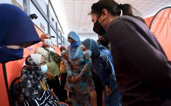 Muhaini (dua dari kanan) bersama Nina Sabrina (kanan) bertanya khabar keadaaan salah seorang wargaemas yang terlibat dalam banjir.