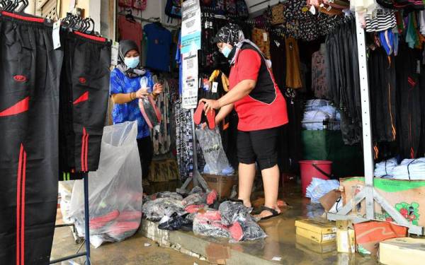Kelihatan para peniaga mengeluarkan barangan mereka dari kedai untuk dibersihkan dan ada yang terpaksa dibuang selepas rosak disebabkan banjir yang melanda beberapa hari lepas. - Foto Bernama