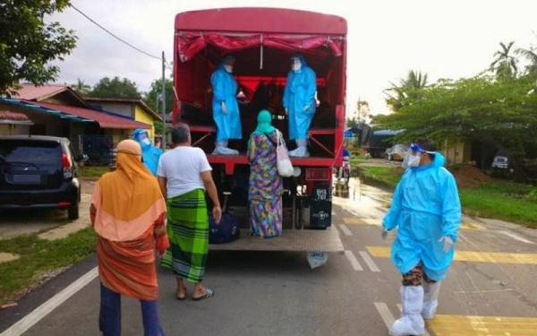 Anggota Balai Bomba dan Penyelamat Rantau Panjang membantu memindahkan lima mangsa banjir yang disahkan positif Covid-19 pada Isnin.