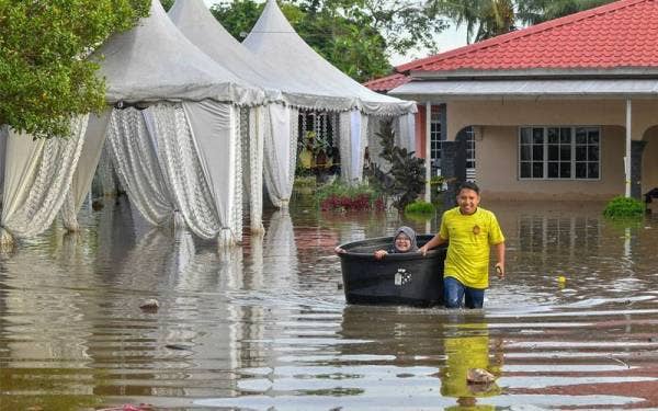 Muhammad Adib Fikri menarik tong tangki air yang dinaiki isterinya ke jalan utama di Kampung Bukit Changgang pada Isnin. - Foto Bernama