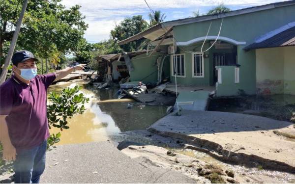 Mohd Norzid menunjukkan keadaan rumahnya yang rosak teruk akibat berlaku mendapan tanah akibat banjir pada Ahad.
