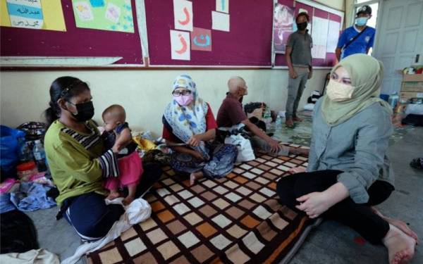 Rina (kanan) beramah mesra bersama mangsa-mangsa banjir ketika melawat Pusat Pemindahan Sementara (PPS) di Sekolah Rendah Agama Bukit Canggang pada Selasa. - Foto Bernama