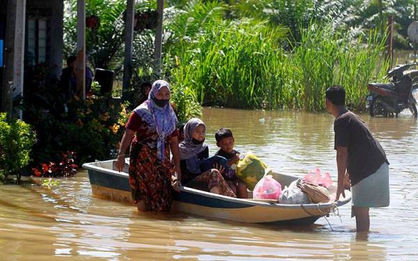 Penduduk kampung meredah banjir untuk memindah perkakasan elektrik dan barangan peribadi menggunakan bot ke tempat yang lebih selamat ketika tinjauan di Kampung Batu 7 Setengah, Changkat Jong pada Selasa. - Foto Bernama