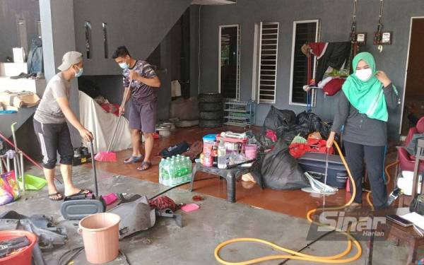 Penduduk di Kampung Haji Mohd Sarip, Klang sedang membersihkan rumah mereka yang terjejas akibat banjir.